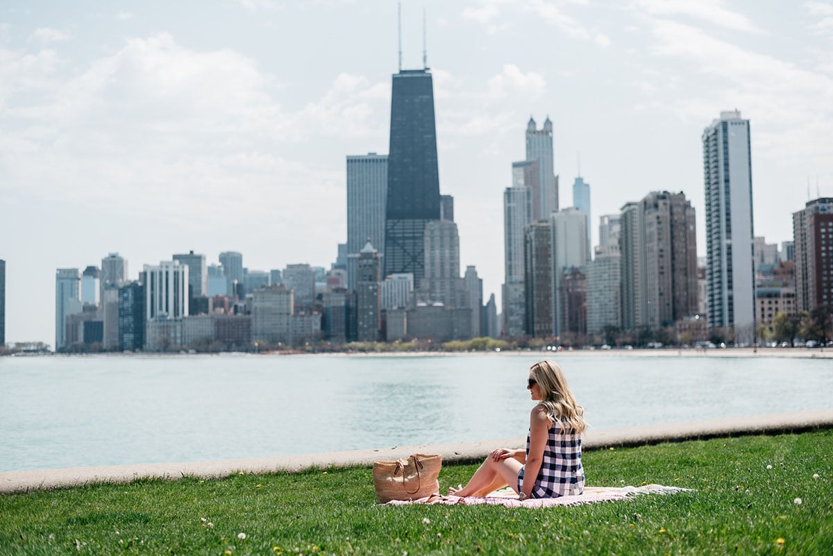 Bows & Sequins wearing a gingham short set having a picnic at North Avenue Beach with the Chicago Skyline in the background.
