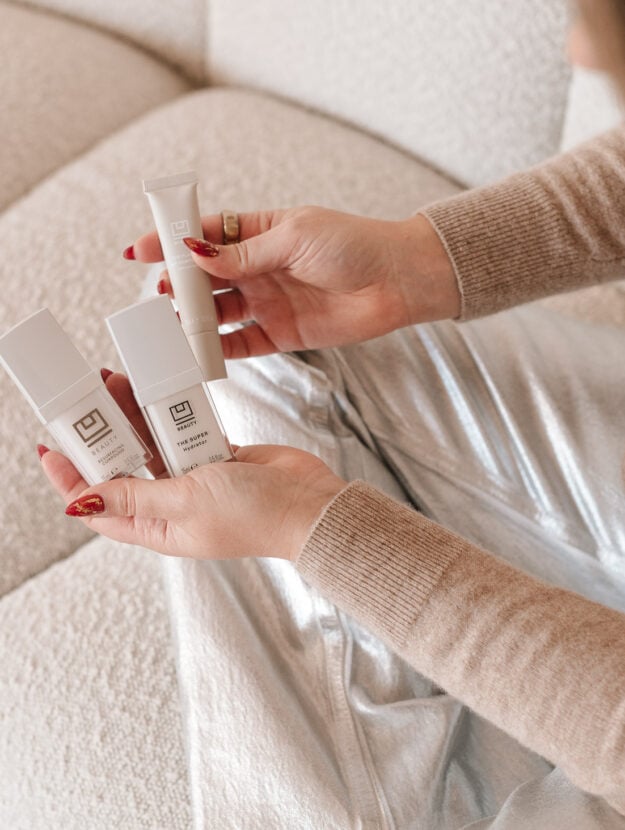 Chicago influencer holding U Beauty Resurfacing Compound and Super Hydrator skincare products on a cream bouclé sofa